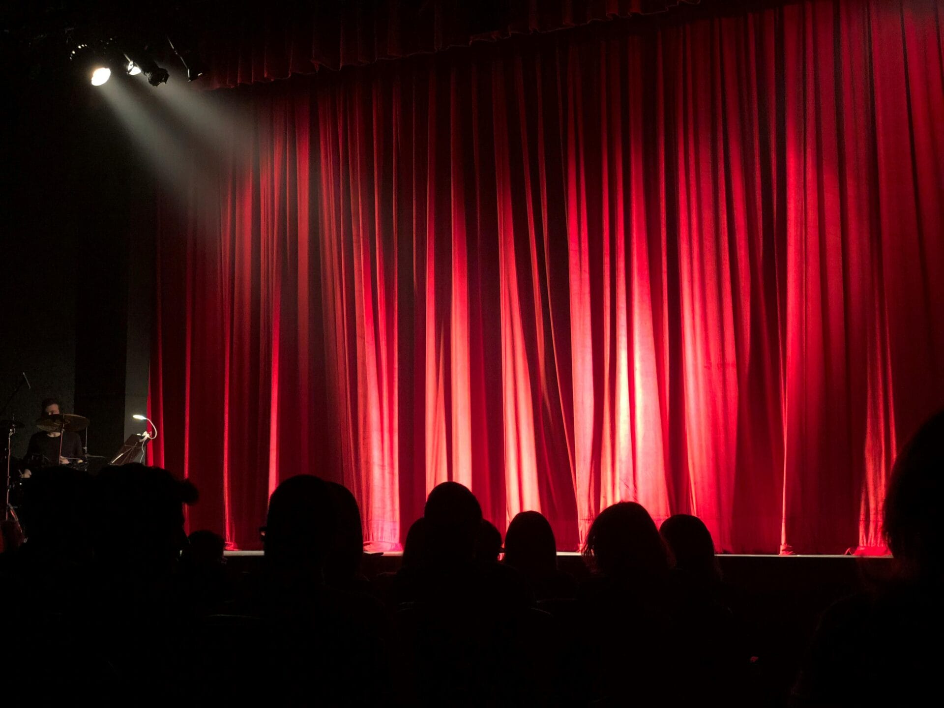 Red curtain with houselights in front of an audience